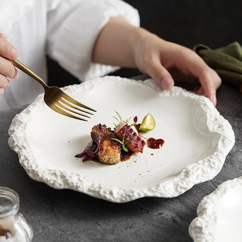 White ceramic dinner plate with an irregular, textured rock-like rim