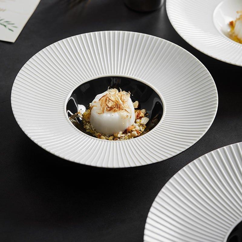 A white plate with a central depression, resembling a hat, filled with food, placed on a black surface.